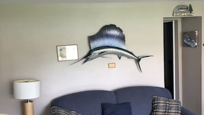 A living room with a blue sofa, two pillows, a wooden coffee table, a lamp, and a wall-mounted decorative piece. - #106-Condo nearby pool and the Gorge shuttle stop (Quincy)