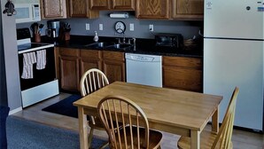 A kitchen with wooden cabinets, a microwave, a coffee maker, a sink, and a dining table with chairs. - #106-Condo nearby pool and the Gorge shuttle stop (Quincy)