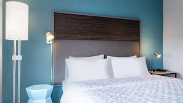 Un dormitorio moderno con una cama grande, una mesita de noche, una lámpara y un aplique de pared.