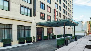 Un hotel moderno con entrada cubierta, amplias ventanas y un camino de acceso pavimentado y limpio.