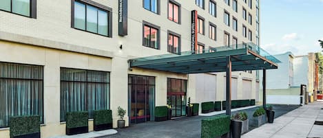 Un hotel moderno con entrada cubierta, amplias ventanas y un camino de acceso pavimentado y limpio.