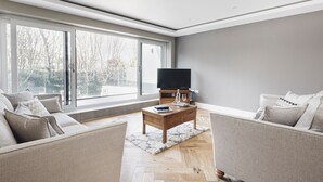Uma sala de estar moderna com uma janela grande, uma televisão de tela plana e dois sofás.