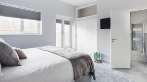 Quarto com cama, janela, porta e televisão.