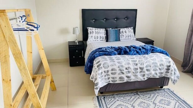 Une chambre à coucher avec un lit, une table de chevet, une échelle en bois et un tapis à motifs.
