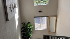 Eine Treppe mit Blumentopf, ein Fenster mit Blick und ein an der Wand befestigtes Kunstwerk.