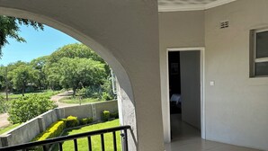 Ein Balkon mit Blick auf einen angelegten Garten und ein Gebäude im Hintergrund.