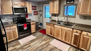 Een keuken met houten kasten, een magnetron, fornuis en een spoelbak.