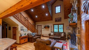 A spacious living area with a wooden staircase, a fireplace, and a cozy seating arrangement.