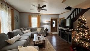 Una sala de estar con sofá modular, una mesa de centro, chimenea y un árbol de Navidad.