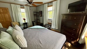 Un dormitorio con una cama grande, un aparador, un televisor y un ventilador de techo.