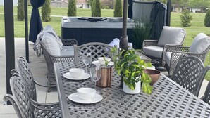 Une terrasse extérieure dotée d’un espace salon couvert, d’un jacuzzi et d’une table dressée pour les repas.