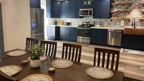 Une cuisine moderne avec des meubles bleu foncé, des appareils en acier inoxydable et un îlot central.