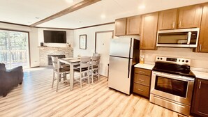 A modern kitchen with wooden cabinets, stainless steel appliances, and a dining area with a table and chairs. - Castle Rock Lakefront Home, with pier, sand bottom, and wrap around deck (Arkdale)