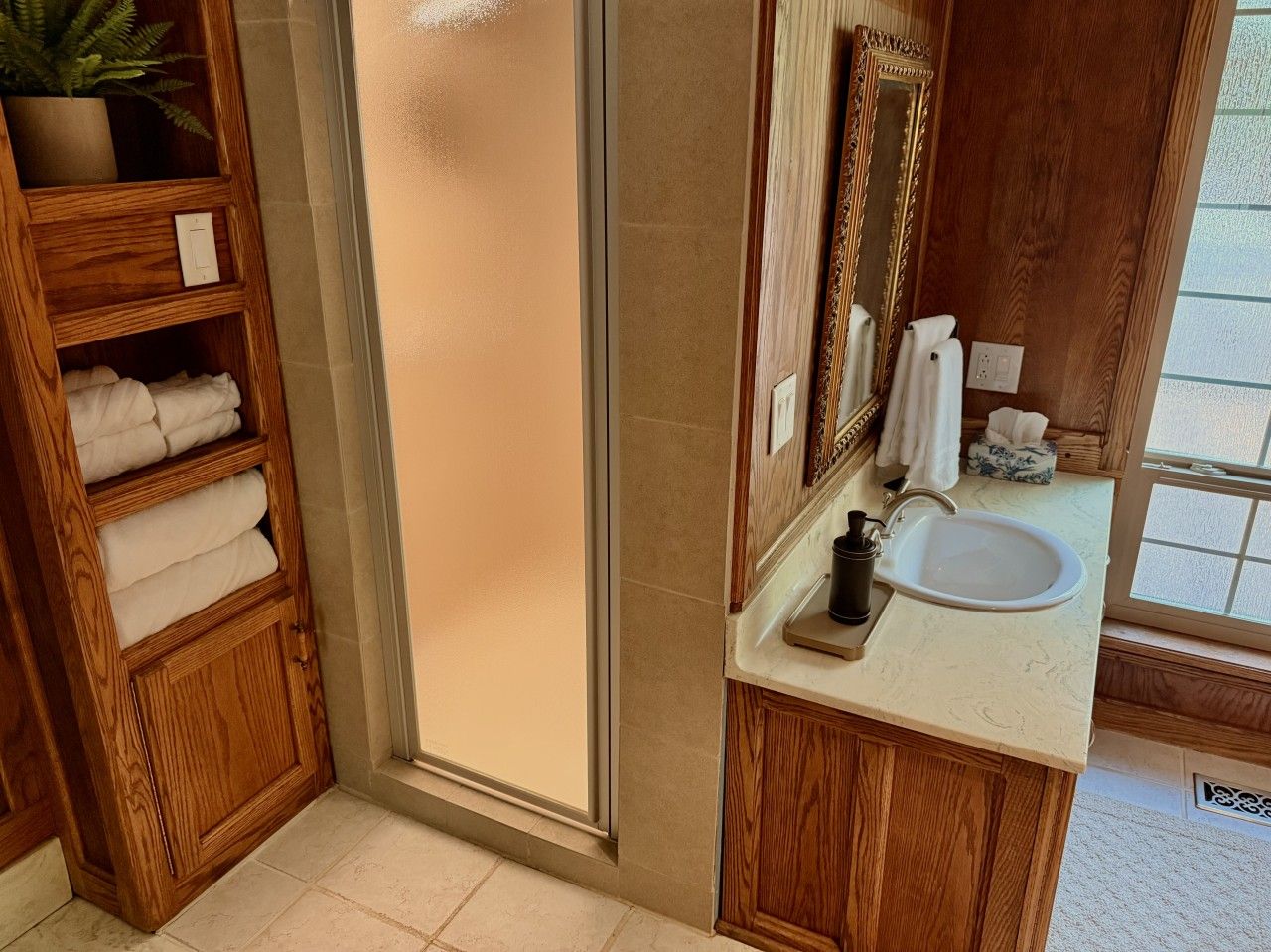 Un bagno con un mobile vanitario in legno, un lavandino bianco, uno specchio e un porta asciugamani.