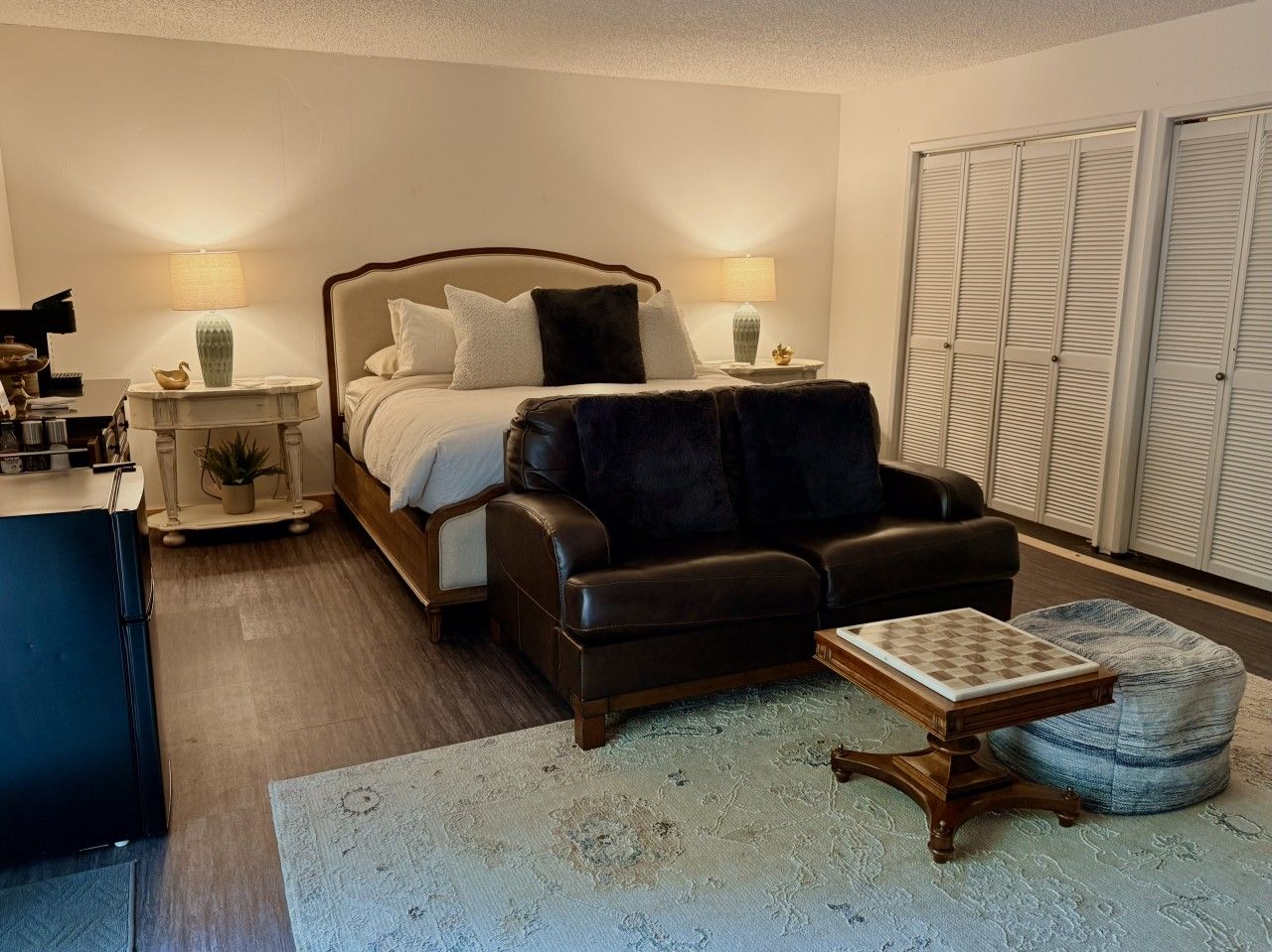 A bedroom with a bed, a leather sofa, a small table, and a wardrobe.