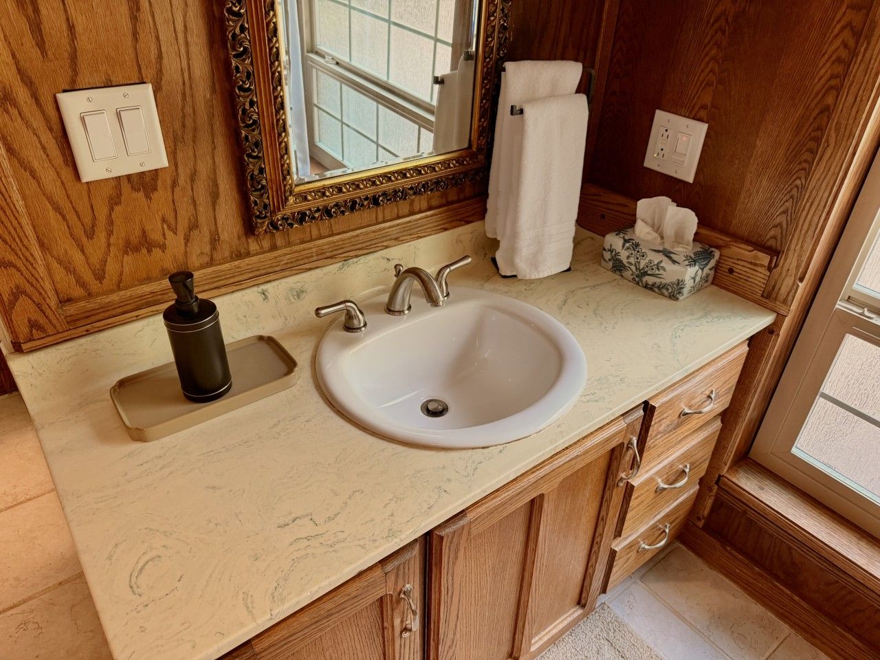 A bathroom with a sink, mirror, towel rack, and a tissue box.