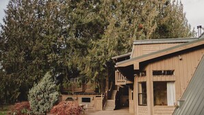 A wooden building with a staircase leading to a deck, surrounded by trees. - Romantic PentHaus Suite - Hot Tub & Sauna (Port Angeles)