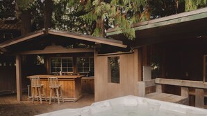 Uma cabana de madeira com hidromassagem, espaço de bar e área externa para sentar.
