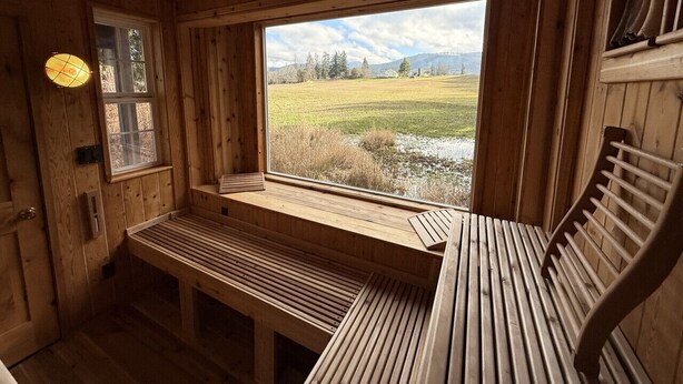 A wooden cabin interior with a bench and a window overlooking a grassy field. - Romantic PentHaus Suite - Hot Tub & Sauna (Port Angeles)