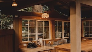 A wooden kitchen with a large island, a sink, and a stove. There are windows and a ceiling fan. - Romantic PentHaus Suite - Hot Tub & Sauna (Port Angeles)