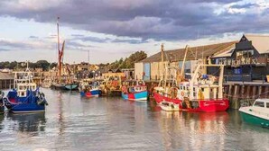 A harbor with various boats docked, a building with a sloped roof, and a cloudy sky. - Perfect Location, dog Friendly Beautiful Home (Whitstable)