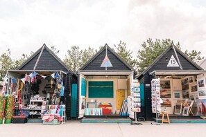 Three small, dark-colored huts with triangular roofs, each displaying different items for sale. - Perfect Location, dog Friendly Beautiful Home (Whitstable)