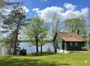 A green house with a brown roof by a lake, surrounded by trees and a grassy lawn. - Classic MN Up North Lake House w/Sauna (Aitkin)