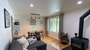 A modern living room with a sofa, dining table, and a black wood-burning stove. - Classic MN Up North Lake House w/Sauna (Aitkin)
