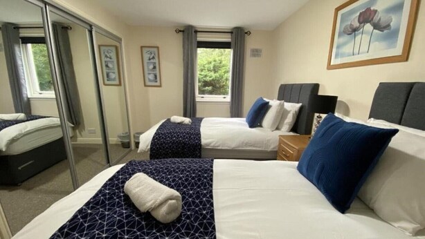Ein Hotelzimmer mit zwei Betten, einem großen Fenster und einem Gemälde an der Wand.
