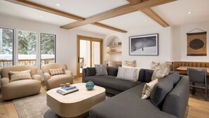 A modern living room with a large sectional sofa, a round coffee table, and a dining area with a wooden table and chairs. - Newly remodeled 4 bedroom condo only 1 block to Bridge St. & ski slopes, fre (Vail)