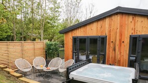 Eine Holzhütte mit Whirlpool, Korbstühlen und einer Terrassenfläche.