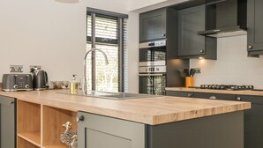 Eine moderne Küche mit dunklen Schränken, einer Holz Arbeitsplatte und Edelstahlgeräten.