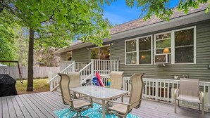 Eine Terrasse mit Tisch und Stühlen, ein überdachter Bereich mit Geländer und ein Haus im Hintergrund.