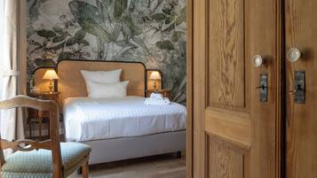 A neatly made bed with white linens, a wooden headboard, and two bedside lamps.