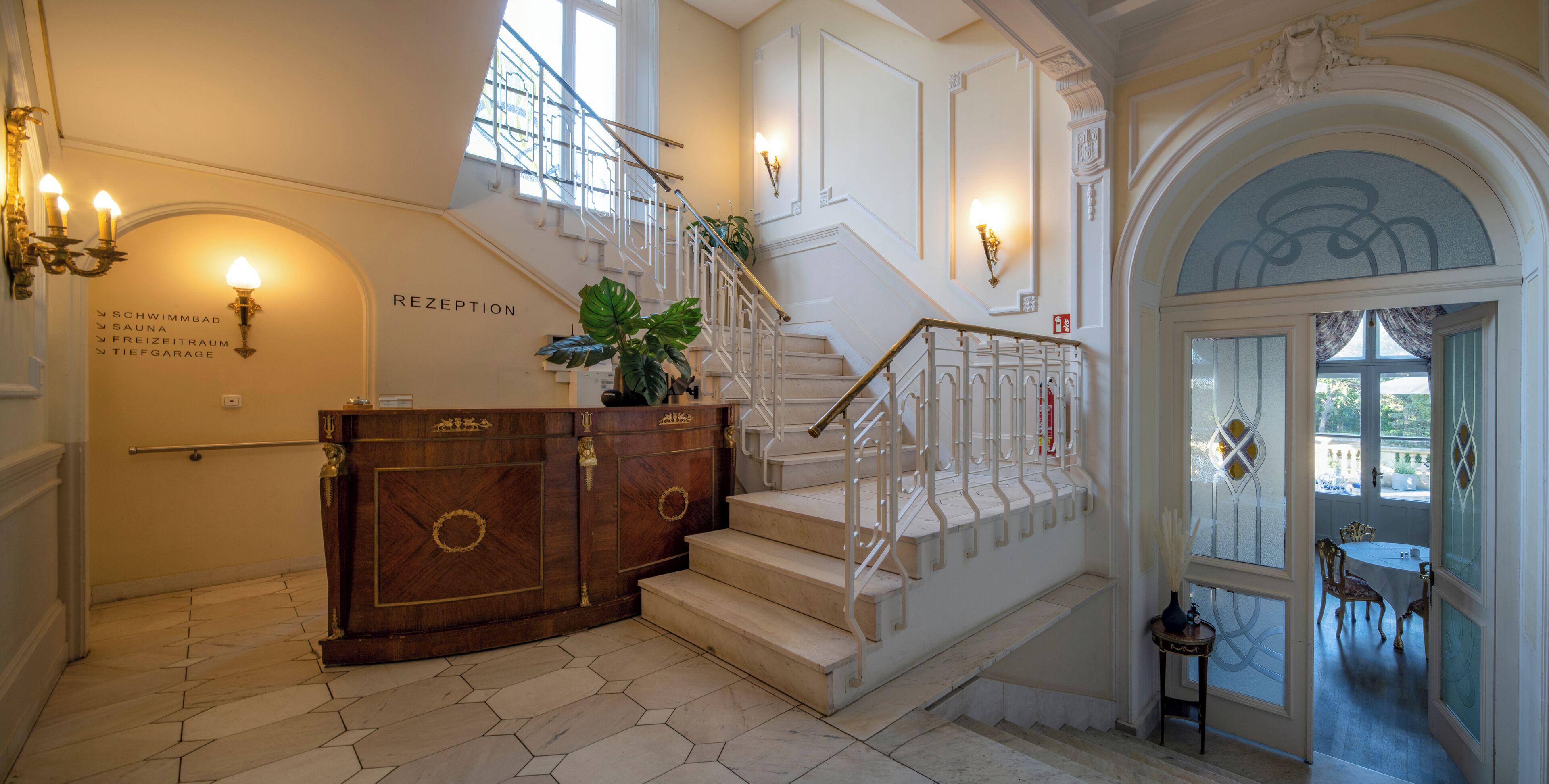 Un grand escalier, un comptoir d’accueil en bois et une plante en pot.
