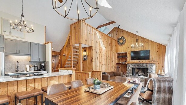 A spacious living area with a wooden interior, a fireplace, and a large TV. - White Mountains Chic Chateau: Updated 3BR+Loft, Sauna, Fireplace & Resort Perks (Campton)