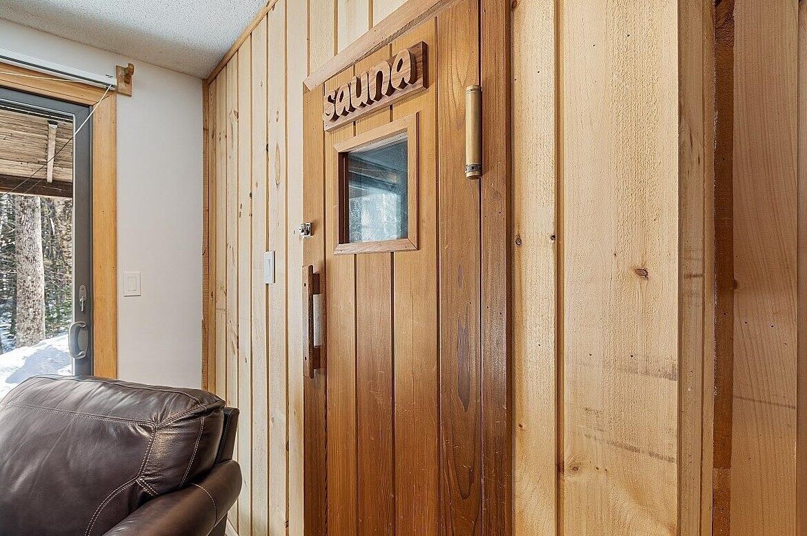 Une porte en bois avec une fenêtre et le mot « sauna » écrit au-dessus.