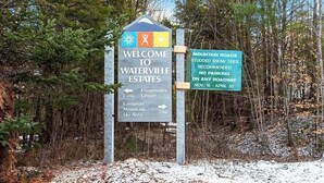 A sign welcoming visitors to Waterville Estates, indicating directions to the community center and mountain area, and advising studded snow tires for mountain roads from Nov. 15 to Apr. 30. - White Mountains Chic Chateau: Updated 3BR+Loft, Sauna, Fireplace & Resort Perks (Campton)