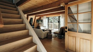 Eine Holztreppe führt zu einem Wohnbereich mit Sofa, Couchtisch und Fernseher.