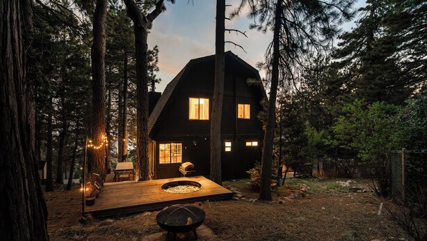Eine Hütte mit einer Terrasse, einer Feuerstelle und Blick auf den umliegenden Wald.