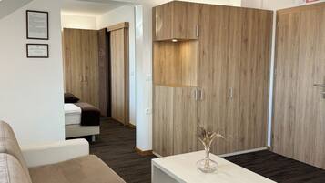A modern hotel room with a sofa, a small table, and wooden wardrobes.