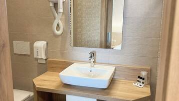 A modern bathroom with a wooden vanity, a white sink, a mirror, and a towel rack.