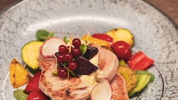 A plate of food with grilled meat, vegetables, and a decorative garnish.