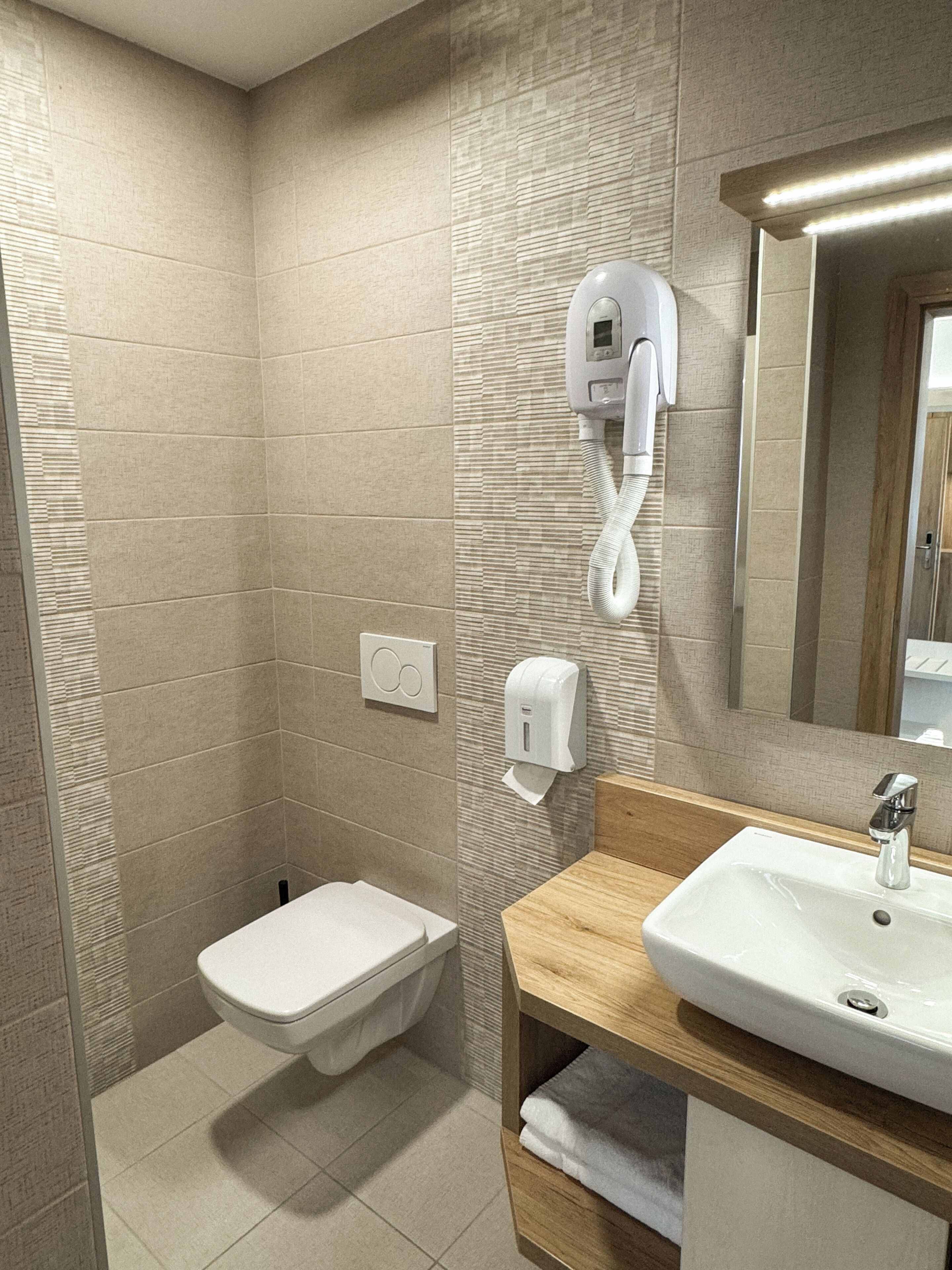 Une salle de bain moderne équipée de toilettes, d’un sèche-mains et d’un lavabo.