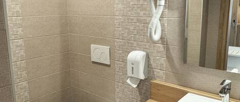 Un baño moderno con inodoro, secamanos y lavamanos.