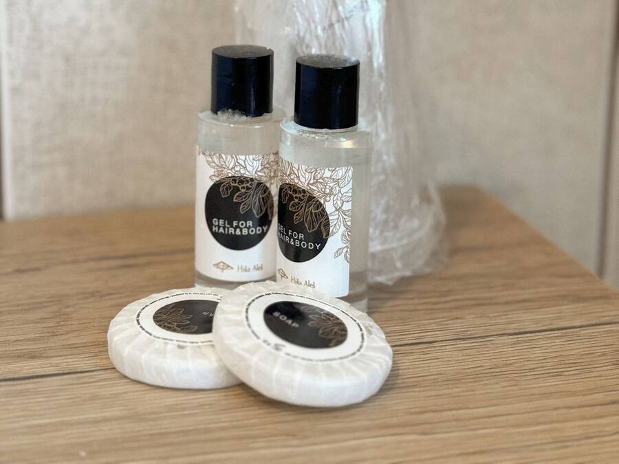 Due flaconi di gel per capelli e corpo e due saponette su una superficie di legno.