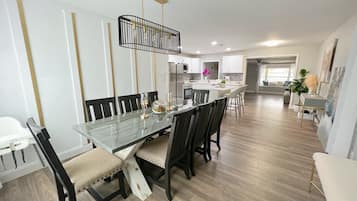 A modern kitchen with white cabinets, a central island, and a dining area with a glass table and chairs.