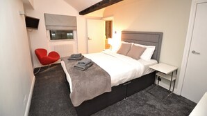 A bedroom with a bed, a red chair, a bedside table, and a TV mounted on the wall. - Loft Piccadilly Circus Apartment (London)
