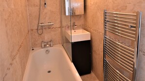 A modern bathroom with a bathtub, a sink, and a shower. - Loft Piccadilly Circus Apartment (London)