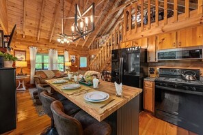 L’intérieur d’un chalet en bois comprend un coin repas, une cuisine et un escalier.